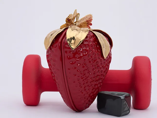 Red strawberry-shaped handbag before props and clutter removed from the shot
