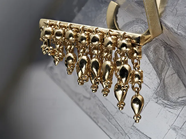 Gold fringe brooch before catalogue retouching and background cleanup