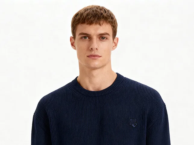 Male model in a navy knitted sweater before on-model cutout and background cleanup