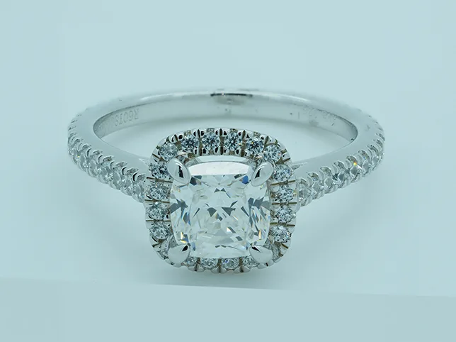 Cushion-cut diamond halo ring before colour correction off a tinted backdrop