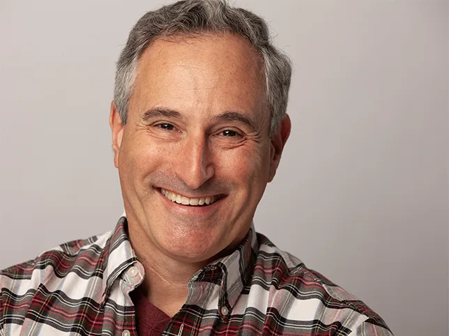 Smiling man in a checked shirt before headshot retouching and background removal