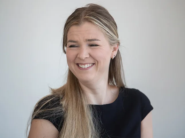 Headshot of a woman laughing before stray hair removal and background cutout