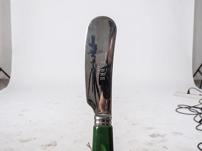 Green-handled butter knife before being masked out of a cluttered studio rig