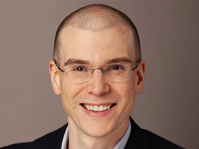Executive in a suit and glasses before corporate headshot retouching