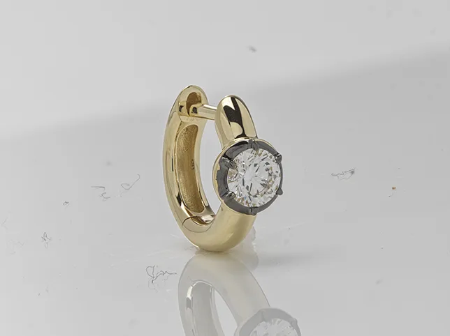 Gold and diamond earring before dust was cleared and the stone sharpened at macro