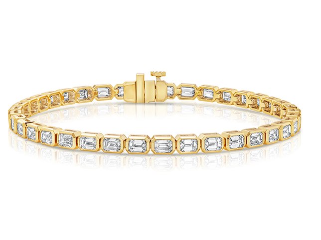 Gold tennis bracelet laid in a curve with a faint reflection along its length