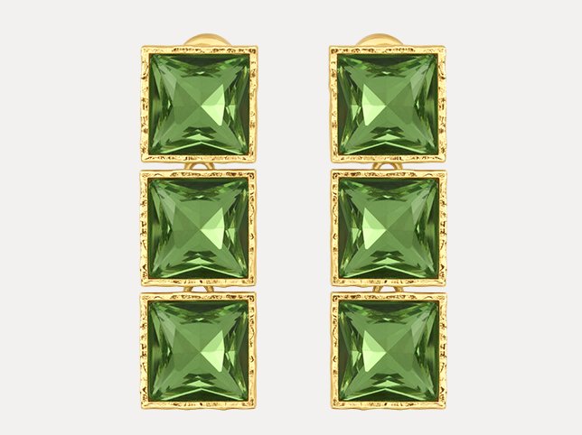 Green gemstone earrings photographed on a faintly tinted off-white background